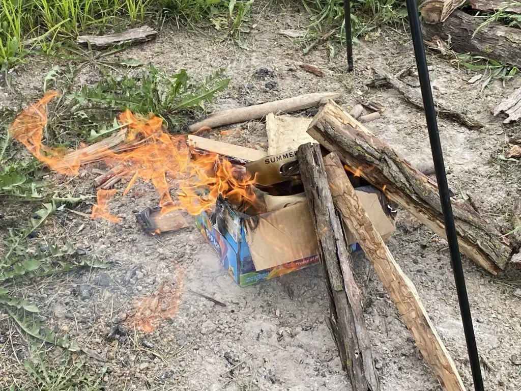 A burning box with firewood on top of it.