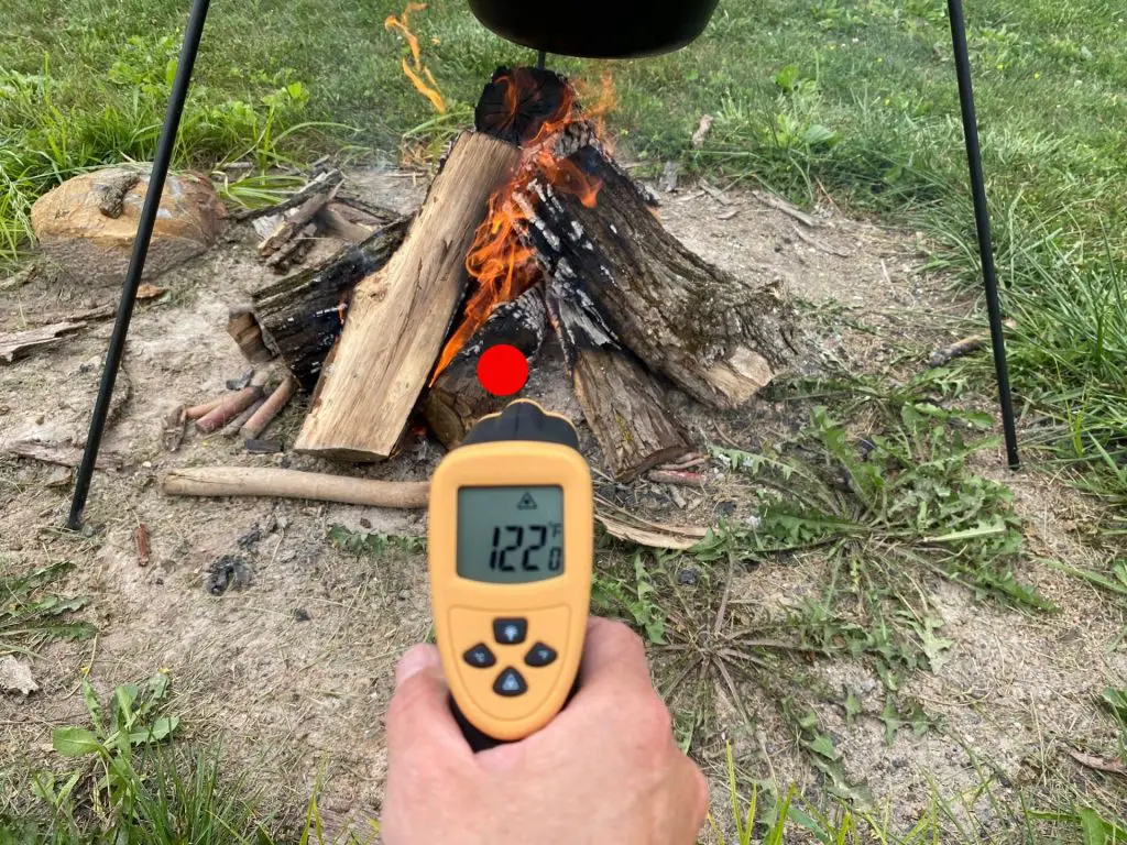 Infrared thermometer pointed at the base of a campfire and showing 122 degrees.