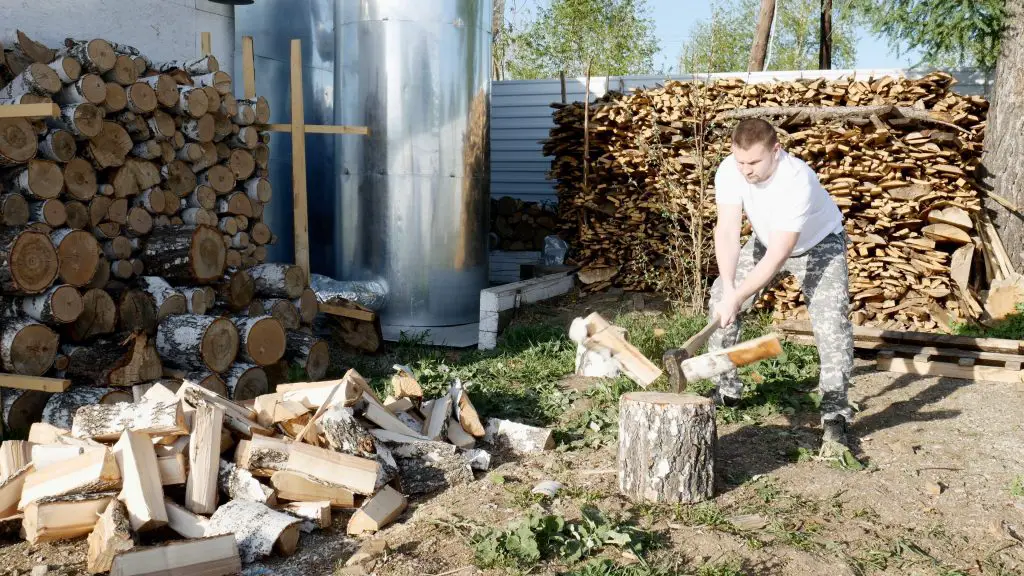 Man splitting firewood in front of a large stack of it