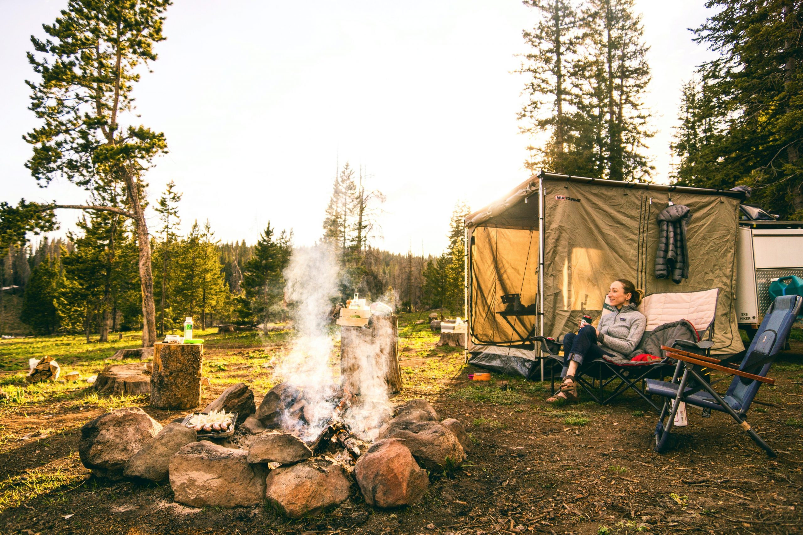 Woman outside her tent camping with a campfire going