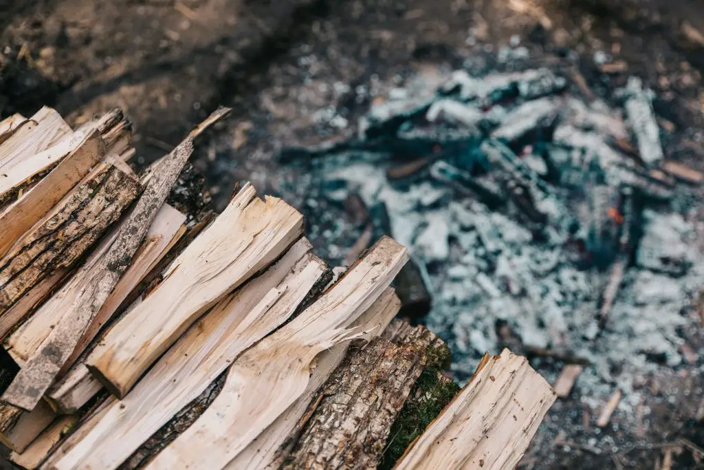 A stack of kindling over the glowing coals of a campfire