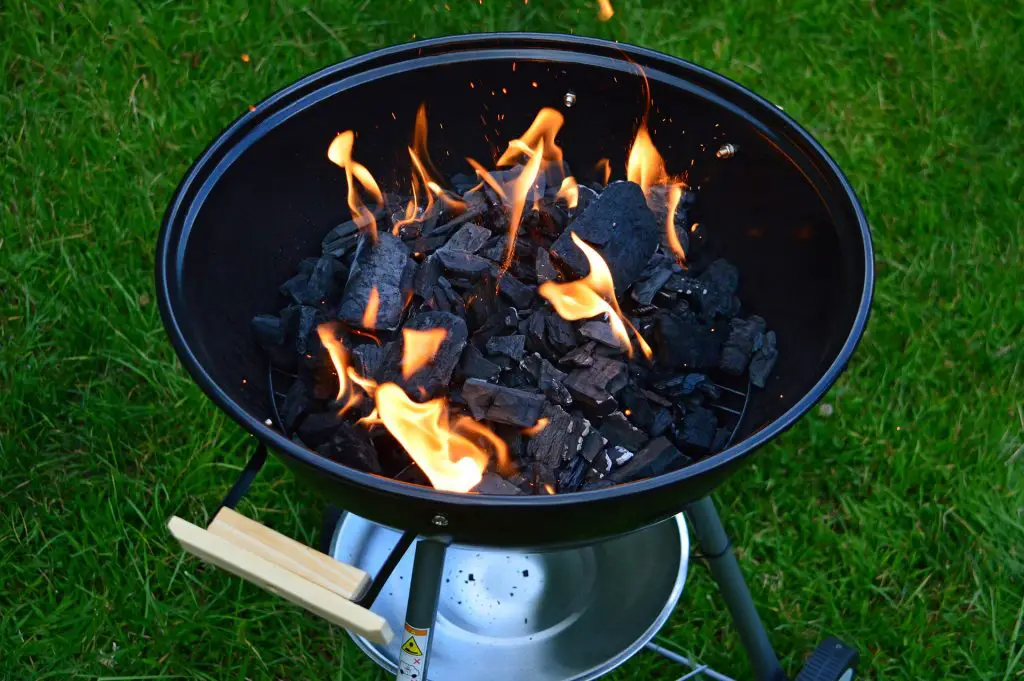 Kettle grill on grass with burning coals
