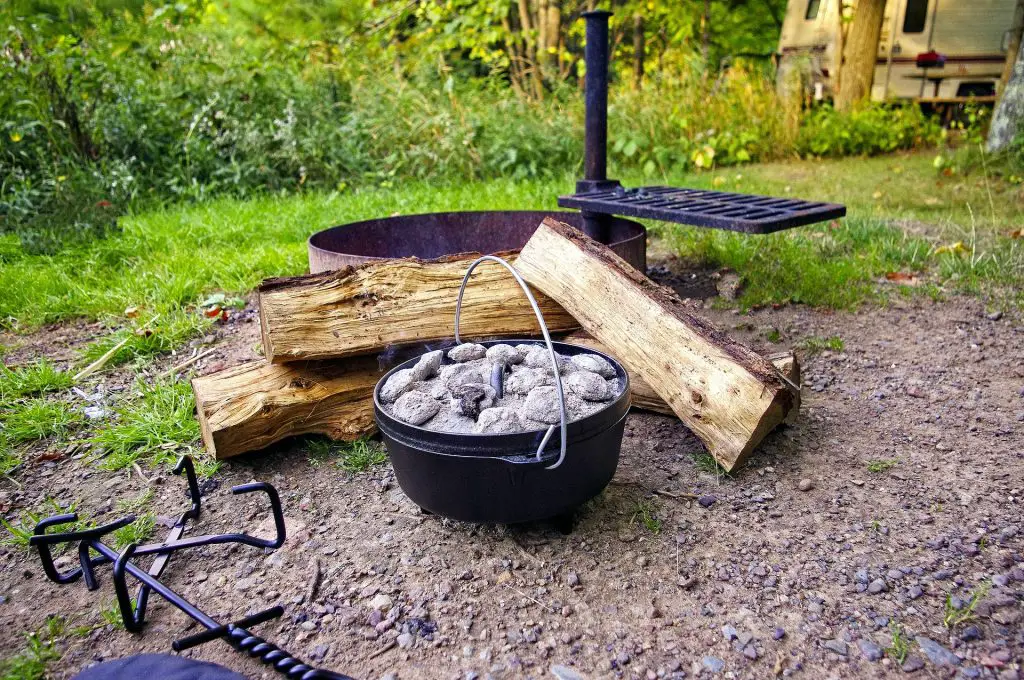 Dutch oven cooking with hot coals on top of the lid at a campsite