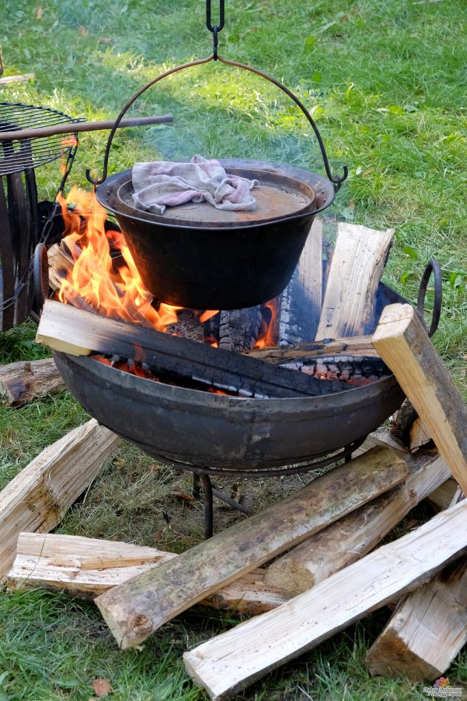 Dutch oven hanging close to a campfire from a tripod