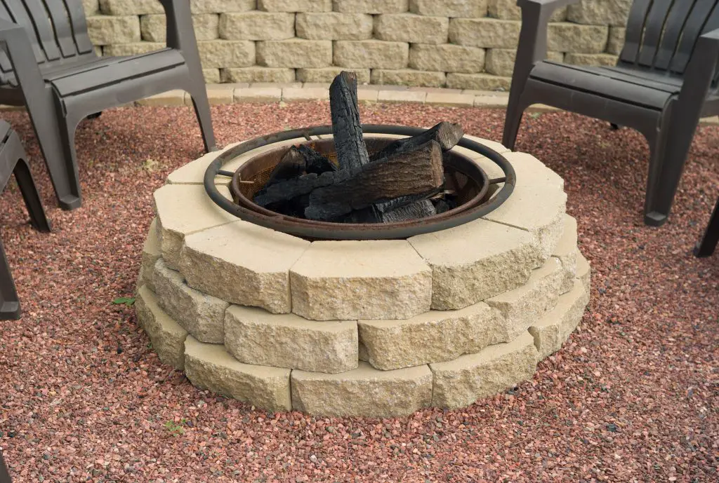 Retaining wall block fire pit using wall block with a lip on the bottom. It also has a fire pit insert inside.