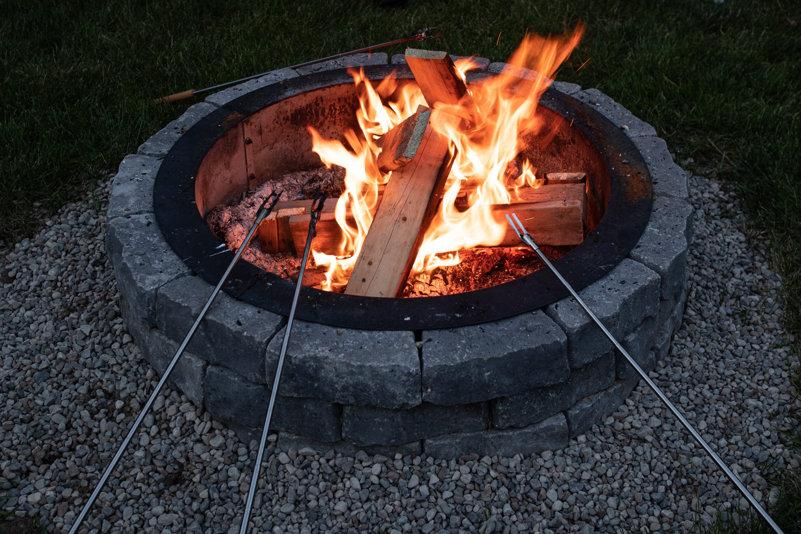 wall block fire pit with people roasting hot dogs over it