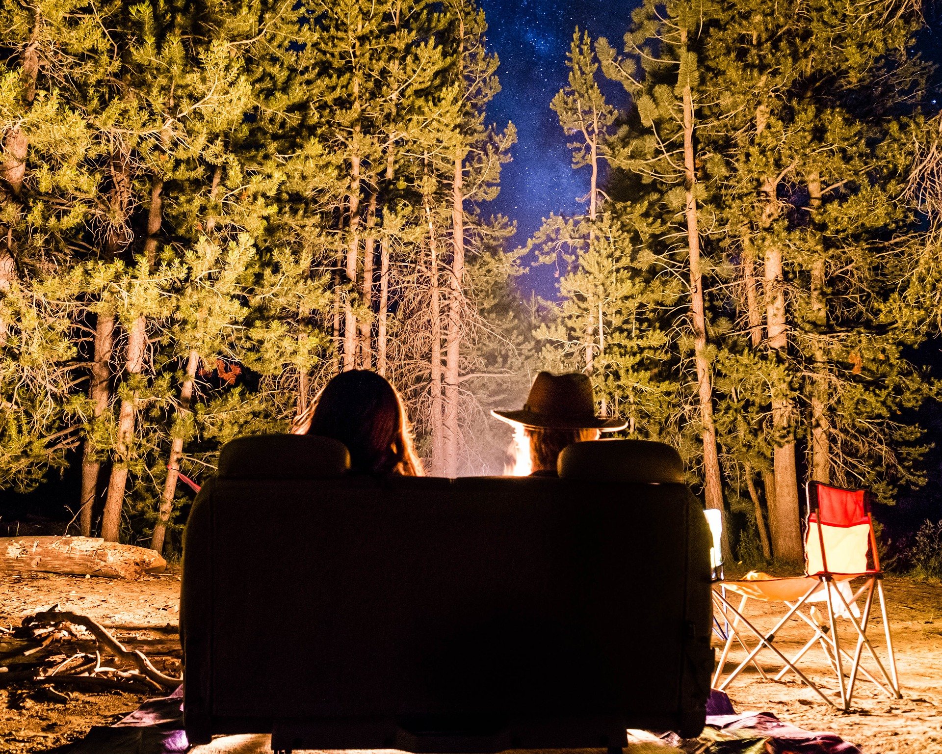 Two people sitting in front of a campfire in a forest