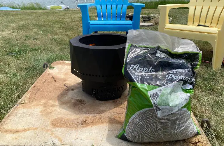 a bag full of apple blend pellets sits on the concrete pad near the campfire
