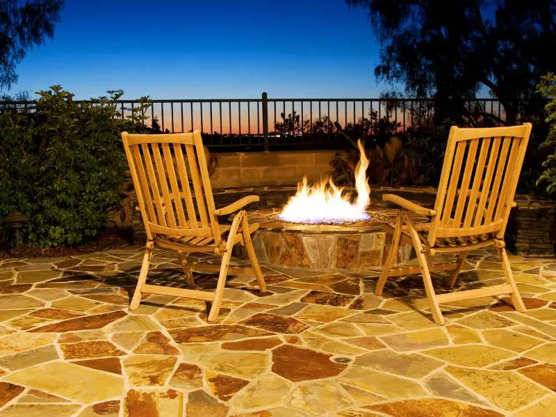 a diy fire pit with wooden chairs surrounding it