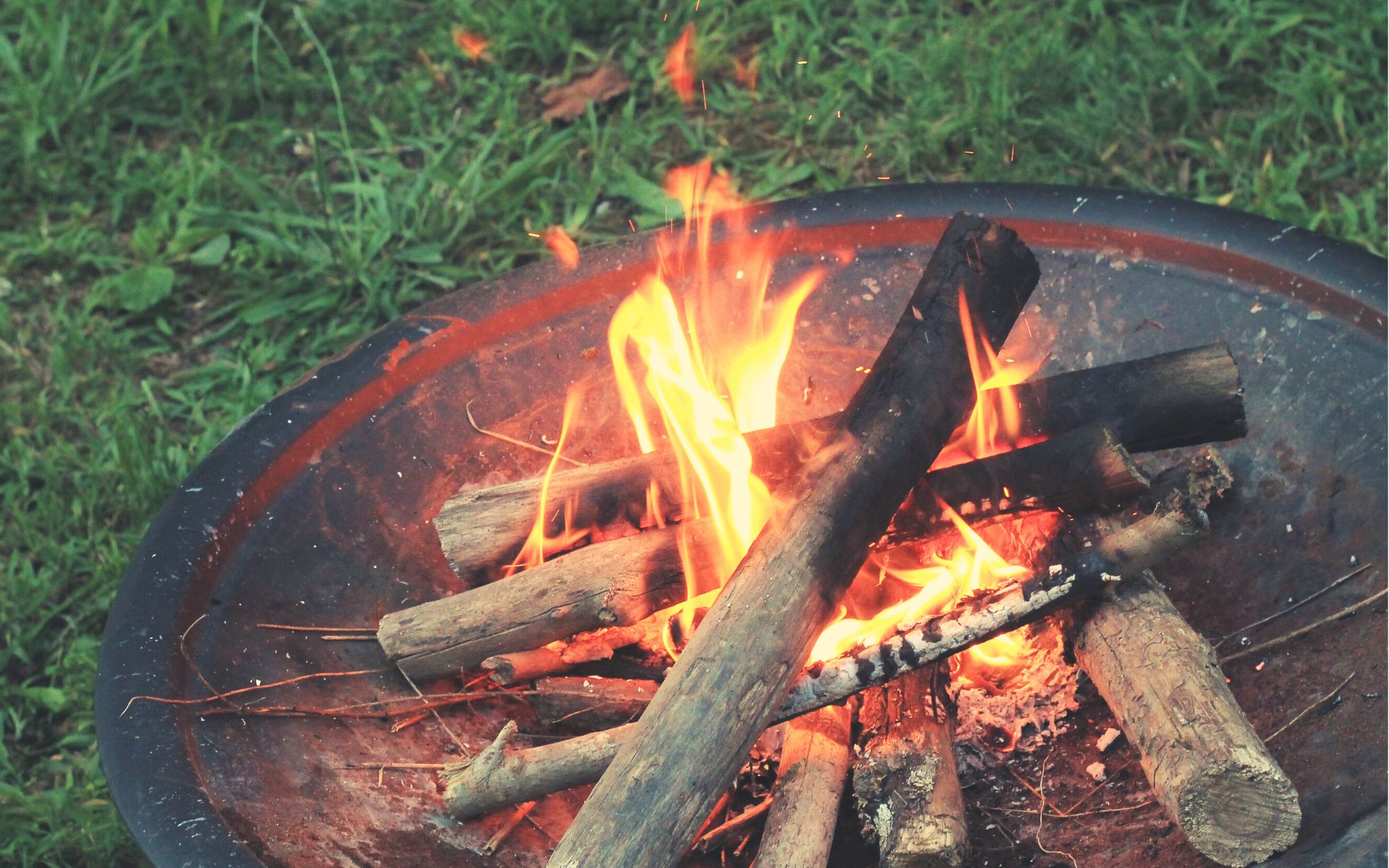 a fire pit burning sitting directly on the grass