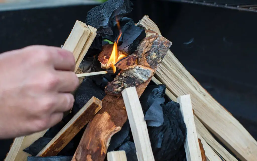 a personal starting a campfire with a match